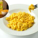 Um homem com um suéter azul sentado a uma mesa com uma caixa de