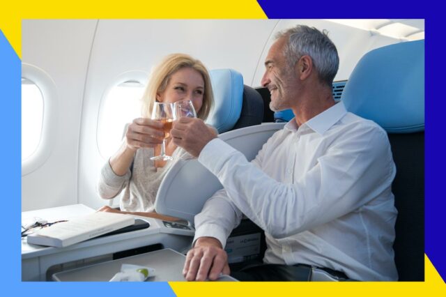 Uma área de estar moderna com assentos cinza e rosa, luzes circulares suspensas e uma parede texturizada.