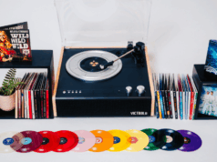 O que é vinil minúsculo? LPs em miniatura que realmente funcionam em toca-discos. Um plano festivo mostra vários discos Tiny Vinyl espalhados sobre uma superfície branca, decorados com enfeites de Natal. No centro está o disco verde translúcido e a capa para