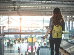 Os estados mais perigosos dos EUA para viajantes individuais revelados Viajante feminina com mochila e bagagem olhando pela janela de um aeroporto.