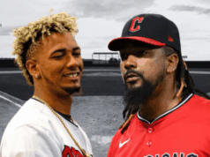 Os jogadores da MLB Emmanuel Clase e Luis Ortiz acusados de apostas esportivas e conspiração para lavagem de dinheiro Os jogadores da MLB Emmanuel Clase e Luis Ortiz acusados de apostas esportivas e conspiração para lavagem de dinheiro. Dois jogadores de beisebol em frente a um campo de beisebol. O jogador da esquerda tem cabelos loiros curtos e cacheados e sorri enquanto veste uma camisa branca e uma corrente dourada. O jogador da direita tem longas tranças escuras, barba e veste uma camisa de beisebol vermelha e um boné preto com um 'C' vermelho. O fundo mostra um campo de beisebol em tons de cinza e luzes do estádio.