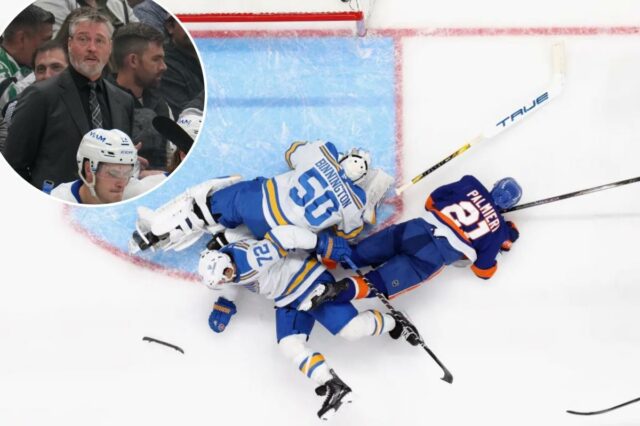 Tiro aéreo de dois jogadores do St. Louis Blues, um goleiro e um jogador do New York Islanders caídos no gelo em frente à rede. Um dos jogadores do Blues perdeu uma lâmina de skate.