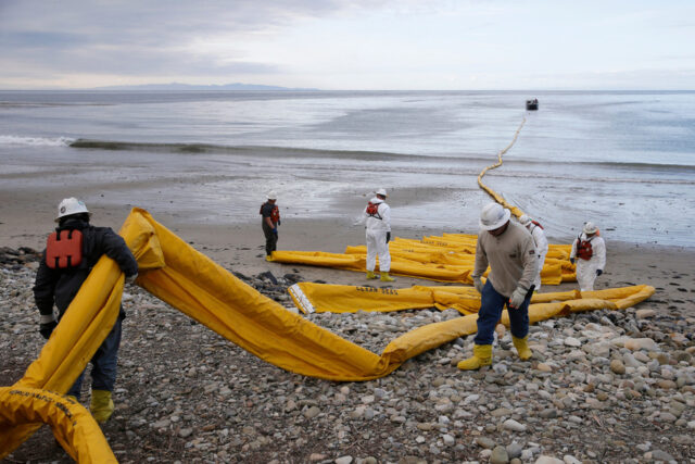 ARQUIVO - Equipes de limpeza removem areia carregada de óleo na praia de Refugio State Beach, local de um derramamento de óleo, ao norte de Goleta, Califórnia, 20 de maio de 2015. (AP Photo / Michael A. Mariant, Arquivo)