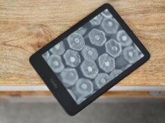 Por que o Amazon Kindle Paperwhite é meu dispositivo móvel mais querido Kindle Paperwhite (2024) deitado na borda da mesa mostrando uma tela com seleção de livros