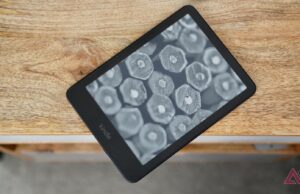 Por que o Amazon Kindle Paperwhite é meu dispositivo móvel mais querido Kindle Paperwhite (2024) deitado na borda da mesa mostrando uma tela com seleção de livros