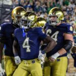 O quarterback dos aspirantes da Marinha, Blake Horvath (11), jogando uma bola de futebol.