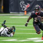 Um jogador do Houston Texans correndo com a bola longe de um jogador do San Francisco 49ers.