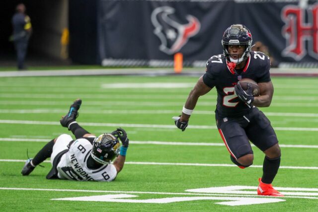 Um jogador do Houston Texans correndo com a bola longe de um jogador do San Francisco 49ers.