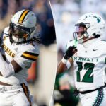 Um jogador de futebol americano do Wyoming com uniforme branco e capacete pegando uma bola de futebol.