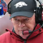 O técnico interino do Arkansas Razorbacks, Bobby Petrino, de boné e fone de ouvido.