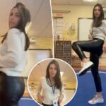 Uma professora vestindo um suéter creme e calça de couro preta, com o logotipo do TikTok no canto superior esquerdo, está em uma sala de aula.