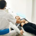 Um profissional médico realizando um ultrassom no abdômen de uma mulher.