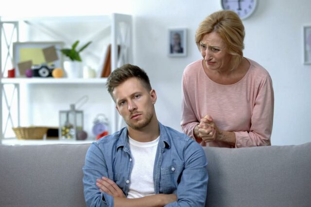 Bebê bebendo de uma mamadeira segurada por uma mulher.