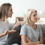 Homem indiano preocupado de óculos sentado em um sofá com a mão no queixo, pensando profundamente.