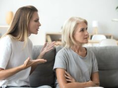 Querida Abby: Estou cansado das visitas inesperadas dos meus sogros Homem indiano preocupado de óculos sentado em um sofá com a mão no queixo, pensando profundamente.