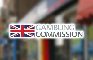 Comissão de Jogos do Reino Unido anuncia atualizações nos regulamentos pós-orçamento O Reino Unido registra enormes ganhos de US$ 22 bilhões na indústria de jogos de azar. Logotipo da Comissão de Jogos de Azar no topo da imagem borrada da loja de apostas