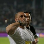 O ex-técnico do Manchester United, Sir Alex Ferguson, sorri enquanto os torcedores cantam parabéns durante a partida da Premier League entre Manchester United e Blackburn Rovers em Old Trafford em 2011, em Manchester, Inglaterra.