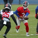O quarterback do New York Giants, Russell Wilson #3, entrega a bola para o running back Dante Miller #25 durante o treino.
