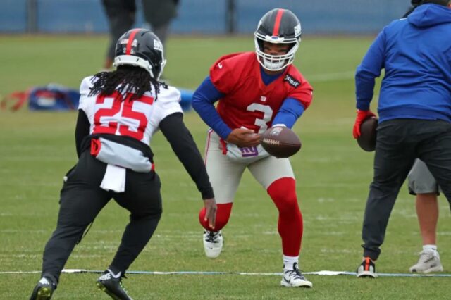 O quarterback do New York Giants, Russell Wilson #3, entrega a bola para o running back Dante Miller #25 durante o treino.