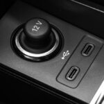 uma pessoa em um carro conectando um cabo USB-C a um smartphone com indicação de bateria fraca