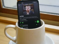 Spotify está finalmente trazendo videoclipes para os EUA Logotipo do Spotify usando fones de ouvido pretos, cercado por ícones flutuantes de notas musicais verdes em um fundo gradiente.