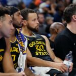 O guarda do Golden State Warriors, Stephen Curry (30), assistiu seu time jogar do banco.