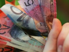 Stoush interestadual de US$ 6 bilhões pairando sobre o polêmico acordo de GST Alguém segurando um punhado de dinheiro australiano.