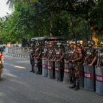Um homem segura um cartaz em frente ao tribunal exigindo a pena capital antes do veredicto sobre as acusações de crimes contra a humanidade pela repressão mortal aos protestos liderados por estudantes em 2024 contra a primeira-ministra destituída Sheikh Hasina, em Dhaka, Bangladesh, em 17 de novembro de 2025.
