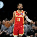 Trae Young, do Atlanta Hawks, fazendo uma careta de dor enquanto segurava o joelho na quadra.