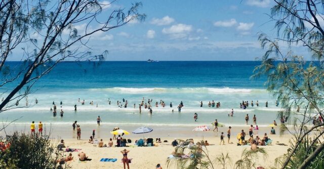 Seascape horizontal de pessoas aproveitando o sol de verão em férias turísticas na praia com areia turquesa ondas céu azul no famoso oceano de surf Byron Bay Austrália