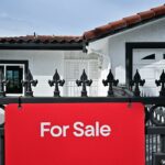 Modelo de casas em uma pilha de moedas e notas.