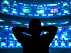 Wall Street está perdendo a fé na IA? young man standing in front of the projection reflected stock market