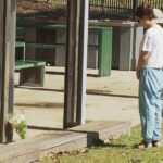 Duas pessoas deixando flores em um parque onde um adolescente teria sido esfaqueado mortalmente.