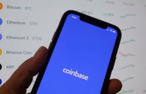 A Coinbase começa a integrar usuários novamente na Índia, planeja uma expansão fiduciária no próximo ano Coinbase's logo on a phone in front of crypto prices