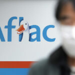 aflac's logo in the background, with someone wearing a mask in the foreground.