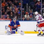 O goleiro do New York Islanders, David Rittich, desvia o disco do jogador do New York Rangers, Carson Soucy.