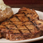 Logotipo do Texas Roadhouse no telefone com gráfico ascendente em segundo plano