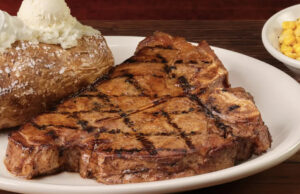 A rede de churrascarias que domina as vendas na América não é LongHorn ou Outback Logotipo do Texas Roadhouse no telefone com gráfico ascendente em segundo plano