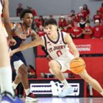 O jogador do St. John's Red Storm, Dylan Darling, dribla a bola de basquete enquanto é defendido por um jogador do Bucknell Bison.