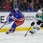 Alexis Lafrenière, do New York Rangers, com o disco, seguido por Esa Lindell, do Dallas Stars.