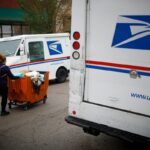 a postal worker worker pushes a mail cart outside a United States Postal Service (USPS) distribution center in Chicago.