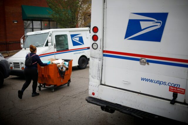 a postal worker worker pushes a mail cart outside a United States Postal Service (USPS) distribution center in Chicago.