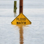 Uma placa alertando os motoristas sobre as enchentes está parcialmente coberta pela água em uma área inundada pelo rio Snohomish, enquanto um rio atmosférico traz chuva e inundações para o noroeste do Pacífico, em Snohomish, Washington, 11 de dezembro de 2025.