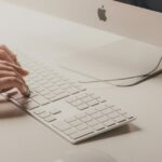 O invasor usou o ChatGPT para enganar os usuários do Mac para que instalassem o MacStealer | Uma foto em close de dedos digitando em um Magic Keyboard conectado a um iMac