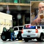 John Drake, atirador de 77 anos, segurando um copo de bebida espumosa.