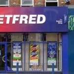 Fora de uma loja Betfred: pintura azul, logotipo da Betfred na placa. O cofundador da Betfred alerta que o aumento dos impostos sobre jogos de azar no Reino Unido pode fechar todas as lojas. Betfred foi multado pela Gambling Commission
