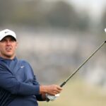 Jogador de golfe com boné branco e top azul marinho segurando um taco de golfe no Alfred Dunhill Links Championship 2025 - primeiro dia.