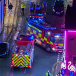 A vista aérea da entrada do Hipódromo de Great Yarmouth mostra um grupo de pessoas conversando, incluindo pelo menos um bombeiro.