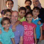 Jovem de boné e vestido em um campo de futebol