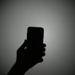 The silhouette of a hand holding an iPhone with the light on.